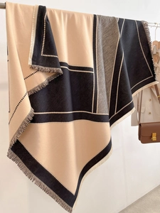 Close-up of color-block knit shawl featuring geometric patterns and soft tassel edges