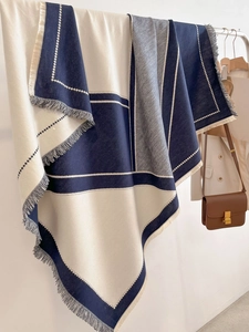 Detail of color-block cashmere shawl with navy and grey geometric patterns and tassels