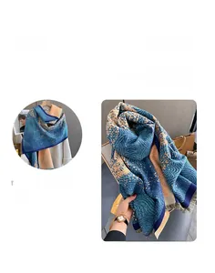 Detail of teal and orange cashmere-feel scarf featuring artistic spiral patterns and tassels