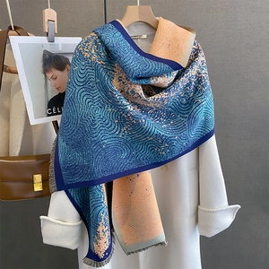 Thick navy and orange cashmere-feel scarf with wavy patterns on a wooden hanger