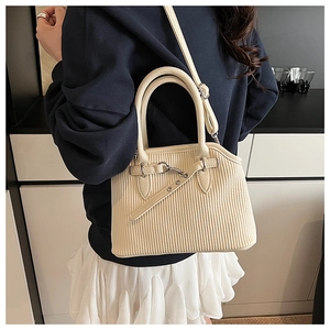 Model wearing off-white pleated tote bag with round handles and metal buckle detail