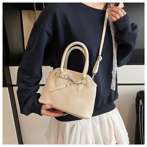 Close-up of beige tote bag with vertical stripes and detachable strap worn by a model