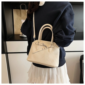 Detail of beige vertical striped tote bag with adjustable strap and buckle on model
