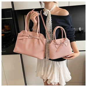 Detail view of pink striped tote and small crossbody bag held by a model in a kitchen