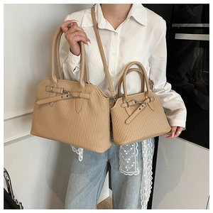 Close-up of pleated beige tote bags in large and small sizes with silver buckle detail