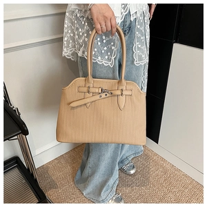 Detail of light beige tote bag with vertical pleated texture and metallic buckle accent