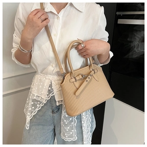 Detail view of beige pleated tote bag with silver metal buckles and dual round handles