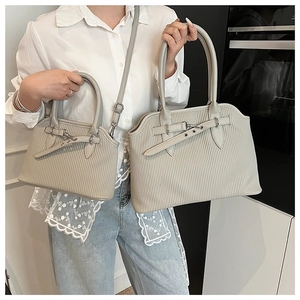 Detail of light gray textured tote bags featuring vertical stripes and metal buckles