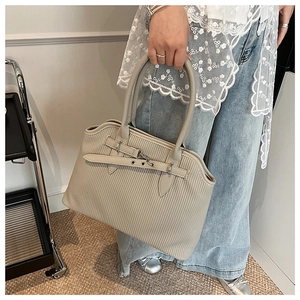 Detailed view of beige pleated tote bag with silver metal buckle and textured surface
