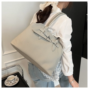 Detail of a large pleated tote bag featuring vertical textures and silver buckle accents