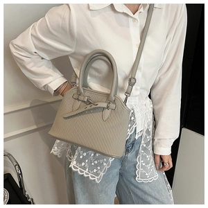 Side view of light grey pleated tote bag with detachable shoulder strap and buckle detail
