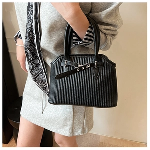 Detail of black tote bag featuring vertical pleated texture and silver buckle handles