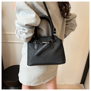 Detailed view of black vertical pleated tote bag with metal buckle and shoulder strap