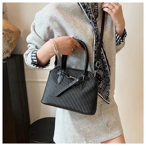 Detail view of black vertical pleated tote bag with sleek leather handle and metal buckle