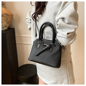 Detailed view of black pleated tote bag with silver hardware on a minimalist background
