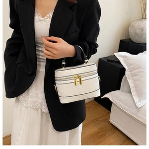 Close-up of white embossed leather handbag with golden zippers and top handle details