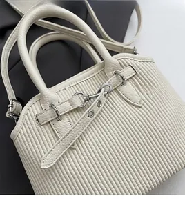 Detail of off-white pleated tote bag showing lychee leather handle and silver hardware