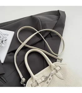 Detail of cream pleated tote bag with silver hardware on a grey blazer backdrop