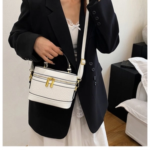 Detail of white lychee texture vanity case bag with gold zippers and adjustable strap