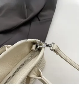 Detailed macro of silver metal zipper and spring buckle on beige leather tote bag