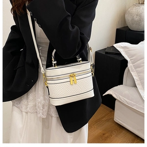 Detailed view of white embossed leather handbag with gold hardware on a modern model