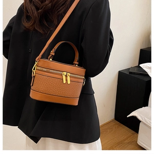 Brown vintage cylinder bag with ostrich leather texture and gold metal zippers