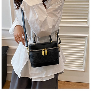 Detail of black textured leather bag with gold hardware and dual zipper closure