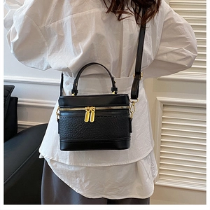 Detail of vintage black lychee texture crossbody bag with gold hardware and strap