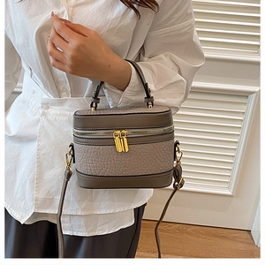 Detail of grey-brown ostrich pattern leather box bag with gold-tone hardware on white shirt