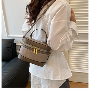 Detail of taupe crocodile texture handbag with gold zipper and adjustable strap