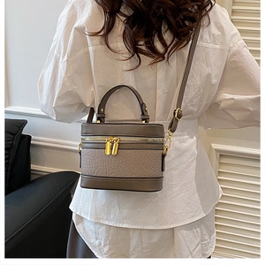 Detail of taupe box bag featuring lychee texture leather and gold metal zipper accents
