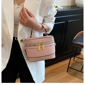 Detail of pink croc-effect box bag with gold double-zipper and top handle for women