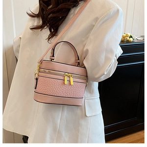 Detailed view of pink lychee grain leather texture and gold zippers on cylinder bag