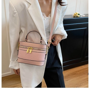 Pink box bag with embossed texture and gold zippers shown on a white blazer outfit