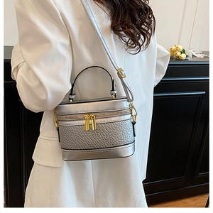 Detail of silver box bag with pebbled leather texture and polished gold hardware zippers