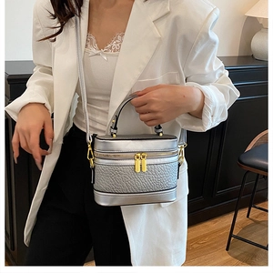 Close-up of silver textured leather box bag with gold zippers and detachable strap