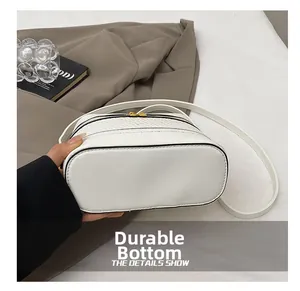 Detail view of the wear-resistant bottom and gold zipper on white stone embossed box bag
