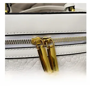 Detail of smooth double gold zippers and white lychee texture leather on the box bag