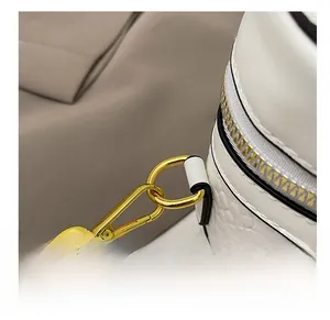 Macro view of white faux leather bag showing gold metal hooks and stitching details