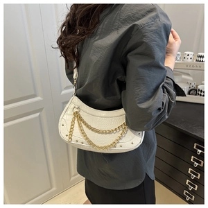 Sac hobo blanc effet croco avec chaîne dorée porté par un mannequin en décor épuré