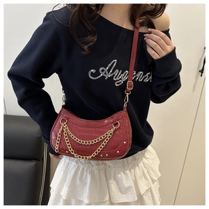 Detail of burgundy crocodile pattern half-moon bag with gold chain and leather strap