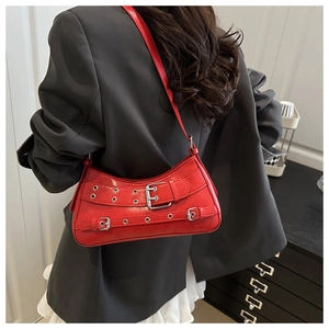 Detailed view of a red leather underarm bag with silver buckles and metallic eyelets