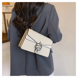Detail of crocodile pattern leather bag featuring a vintage metal snake clasp on chain strap