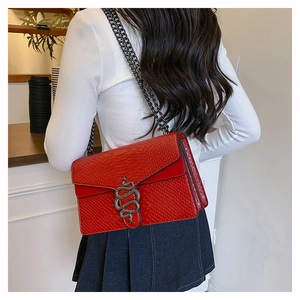 Detail of red faux snakeskin bag featuring a vintage metal serpent head buckle and chain strap