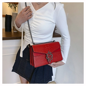 Detail of red faux python skin shoulder bag with a silver snake-shaped buckle clasp