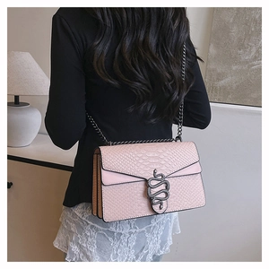 Detail of pink snake-embossed leather crossbody bag featuring silver serpent buckle