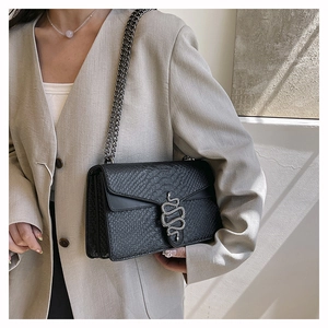 Macro detail of black crocodile pattern leather bag with silver snake head buckle