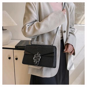 Detail of silver snake-head buckle and faux crocodile texture on black crossbody bag