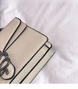 Detailed macro view of the cream snakeskin textured leather with vintage snake metal clasp