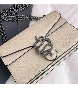 Close-up of cream snakeskin texture and iconic dark grey metal snake head buckle